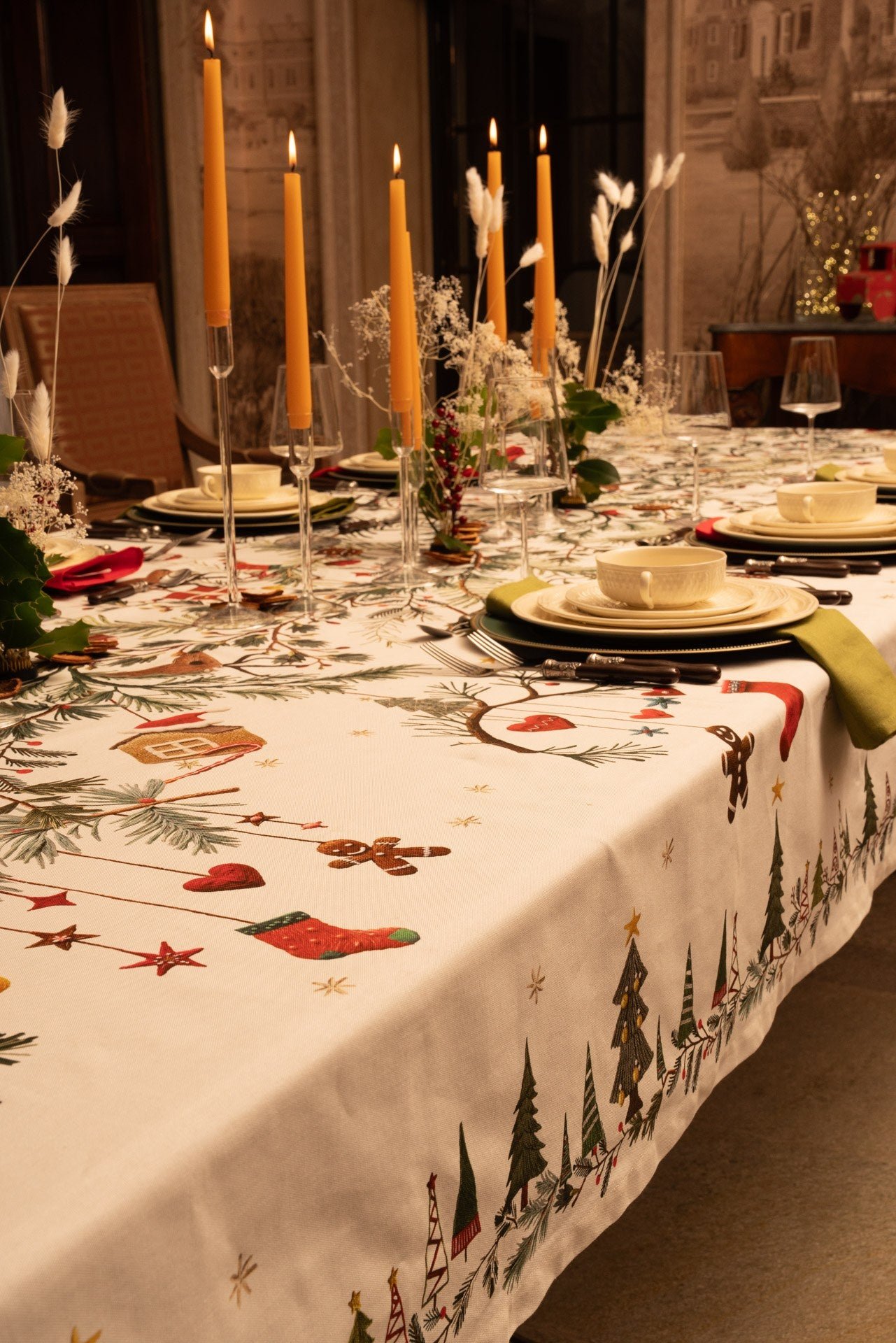 Rudy printed cotton Christmas tablecloth with a fir tree and garland border on a holiday table